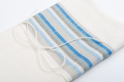 Weißes Küchentuch mit grauen und blauen Streifen.