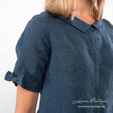 Die kurzen Ärmel des blau gestreiften Leinenkleides sind mit Schleifen