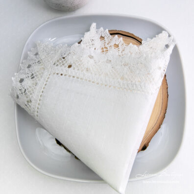 Milchweiße Leinenserviette mit kleinen Rauten, Hohlsaum und Spitze