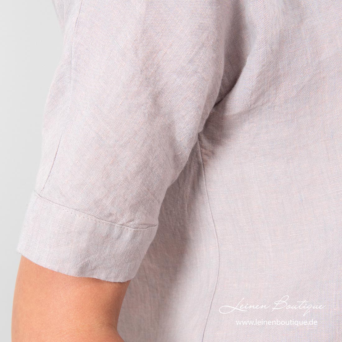 Der Leinenstoff der Bluse ist aus hellgrauen und blassrosa Garnen gewebt